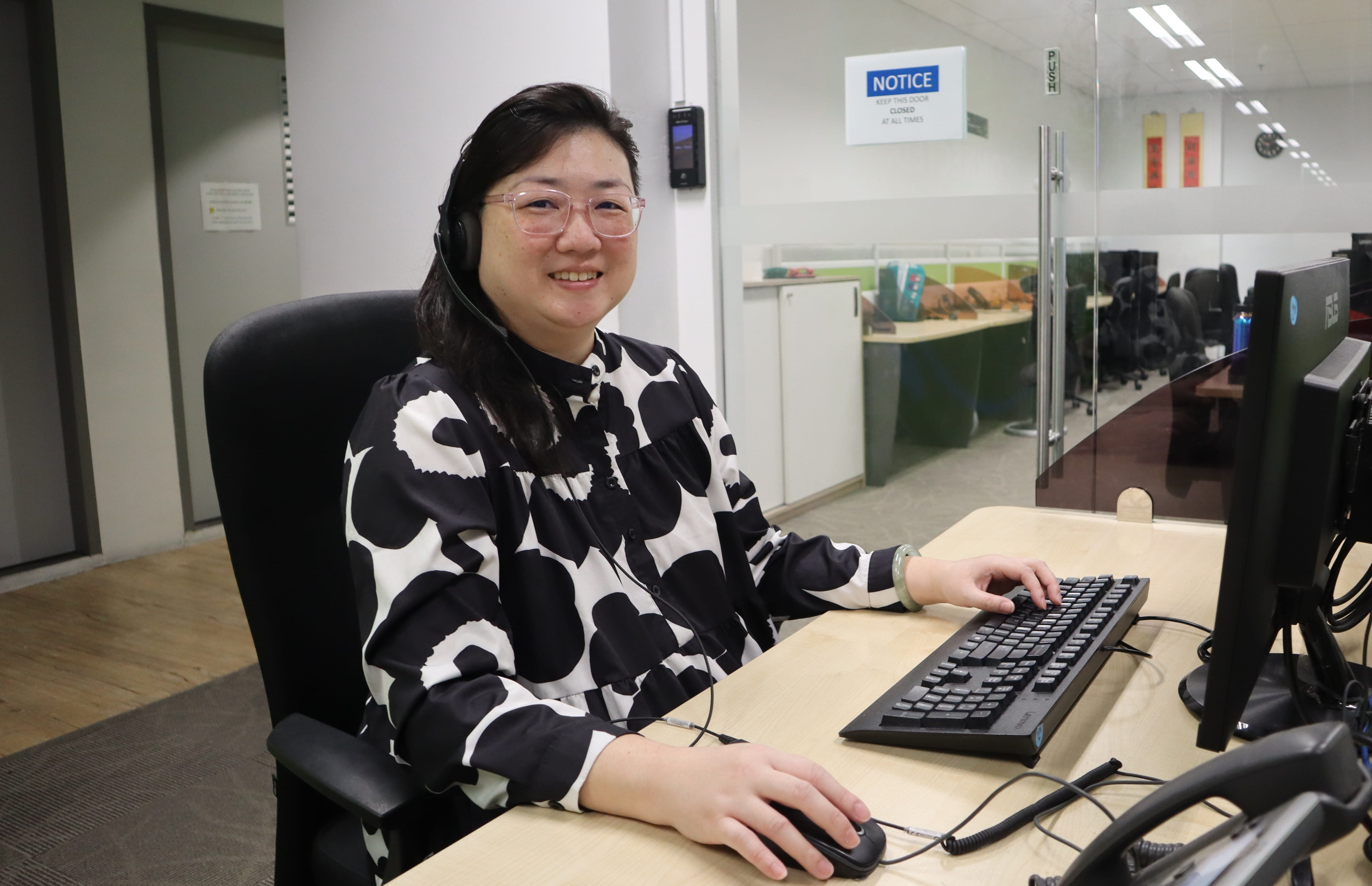 Mdm Ten sitting at her desk performing her job as a call centre operator